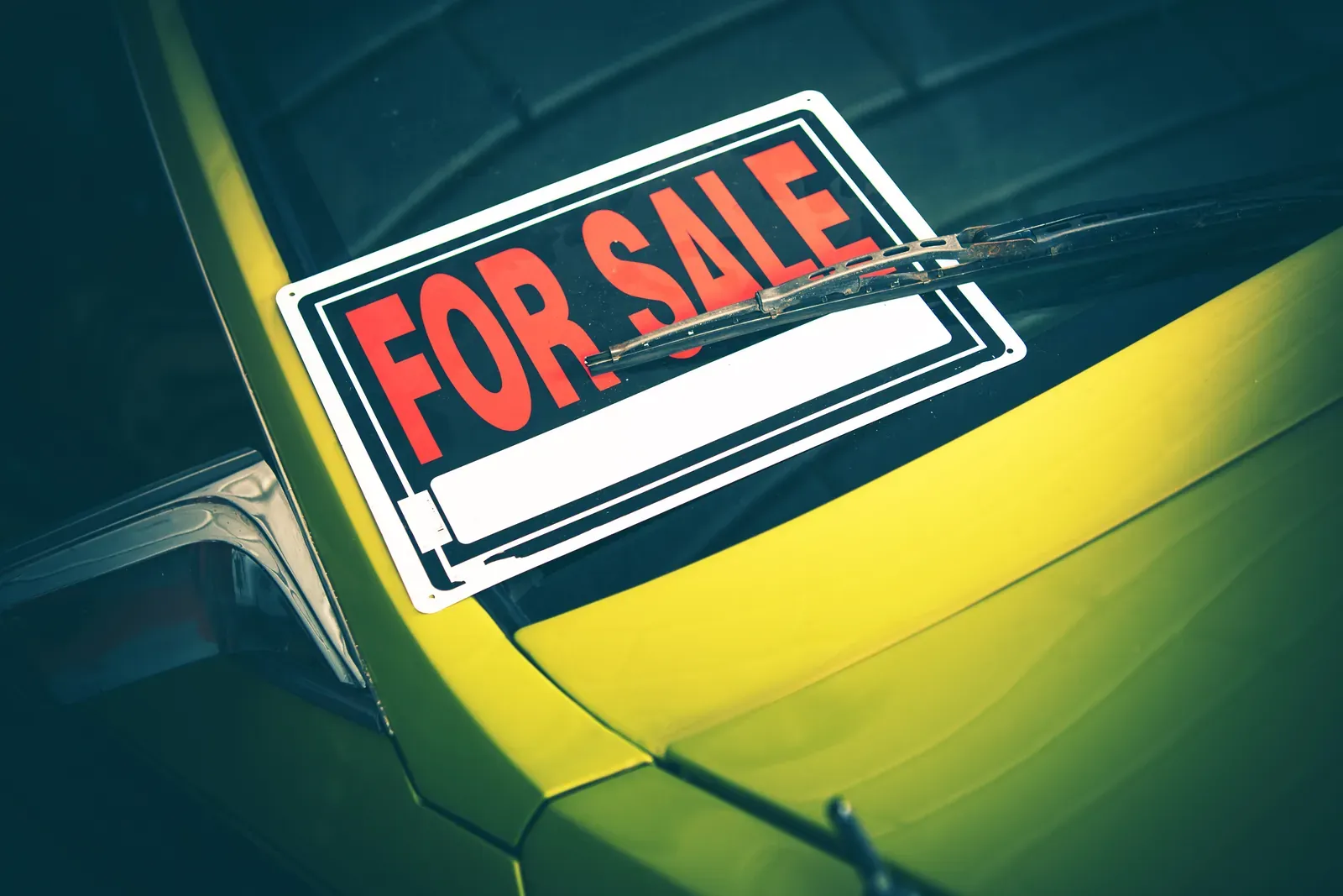 For-sale sign sitting in the windshield of a used car