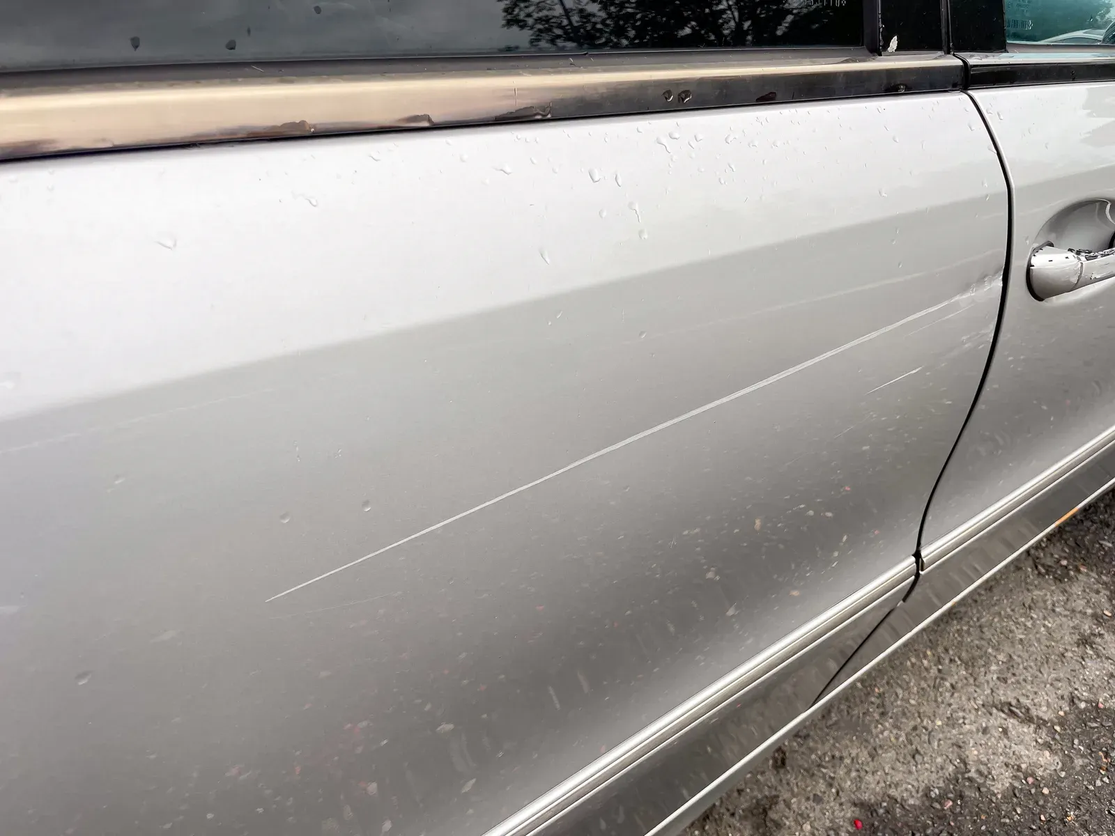 Long scratch down the side of a parked car before repair