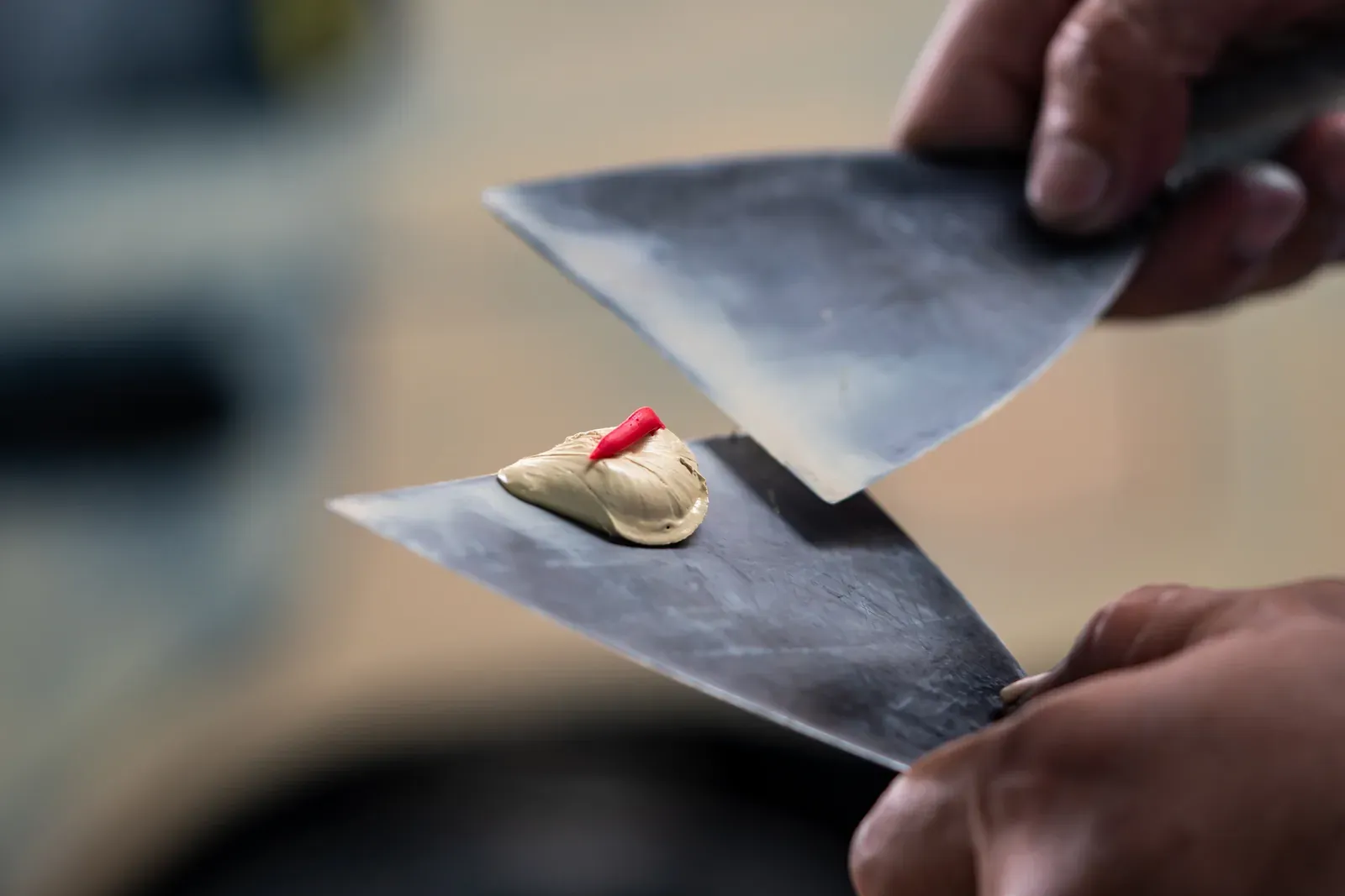 Technician working body filler on a panel inside a busy repair shop