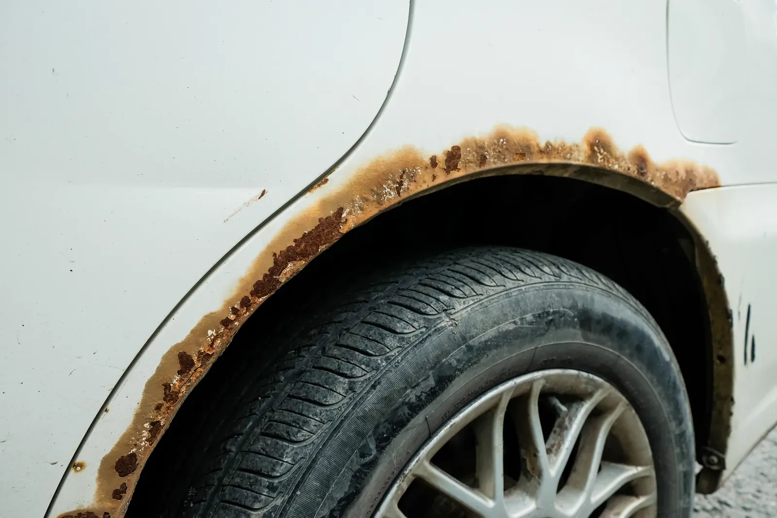 Rust spreading along the wheel arch lip of a car’s rear quarter panel