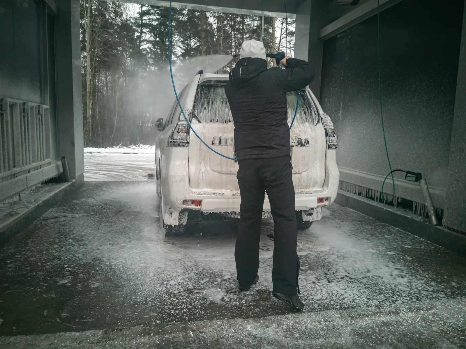 Car being rinsed clean of winter road salt at a wash bay